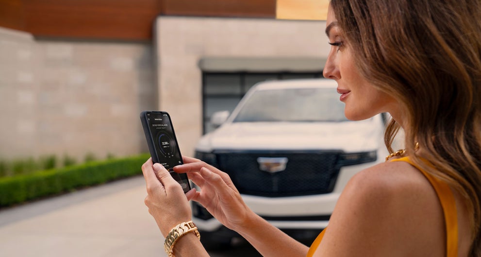 lady checking her mobile with a Cadillac vehicle background | Mataga Cadillac in Stockton CA
