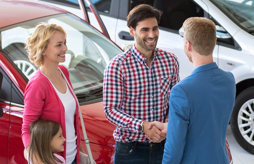 Adult shaking a man's hand next to woman and child